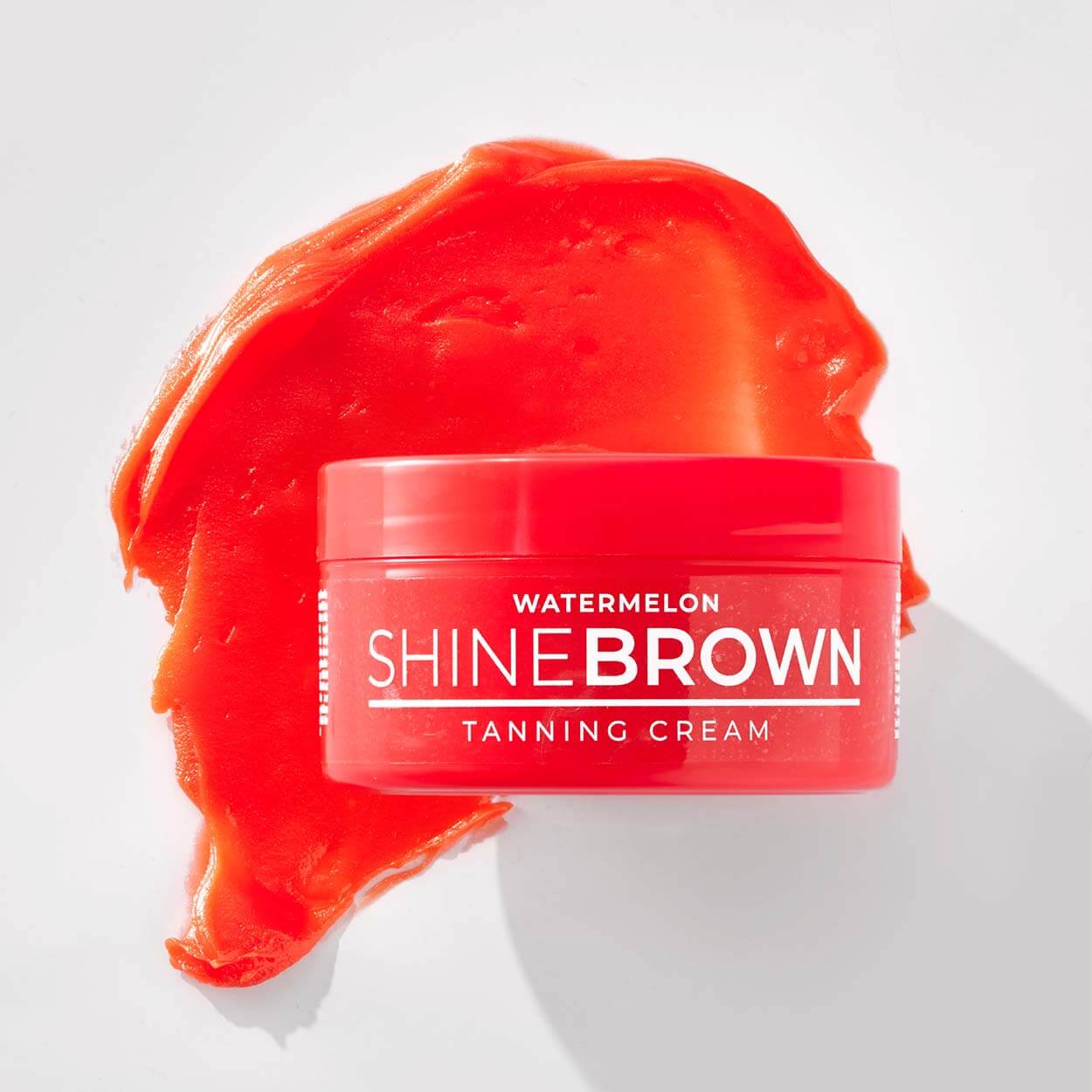 Shine Brown Watermelon tanning cream with smeared tanning cream in the background.